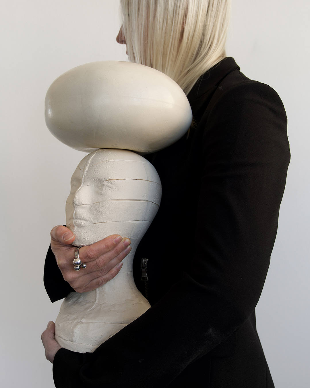 Elizabeth cradles an unglazed white porcelain mannequin. These archetypal mannequins expose their life experience in the beauty of scars, in the unglazed body of the clay and in the seams of production.