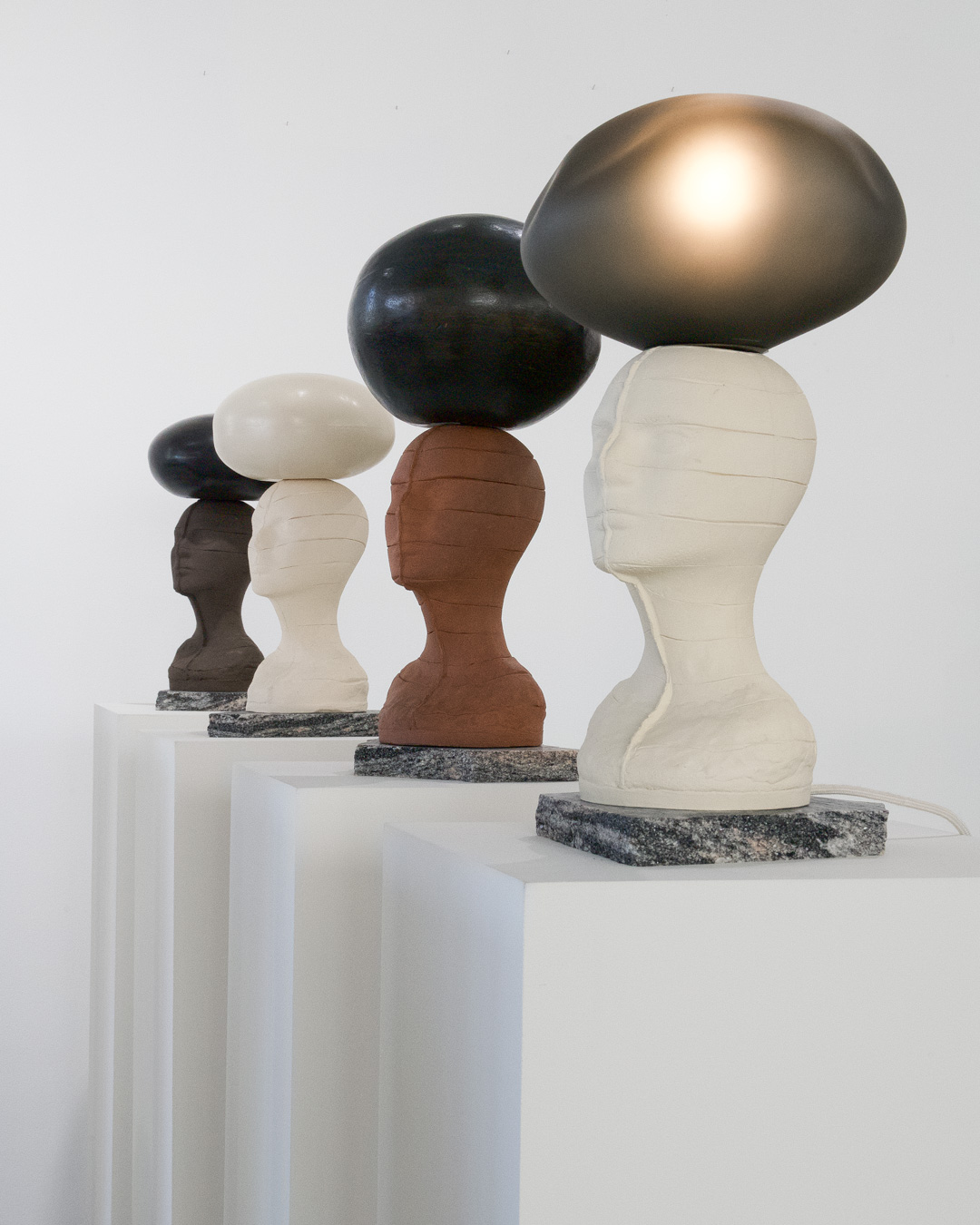 Installation view of “What We Carry.” Mannequin heads, typically used for displaying objects relating to personal adornment, support a variety of orbs in the act of carrying.