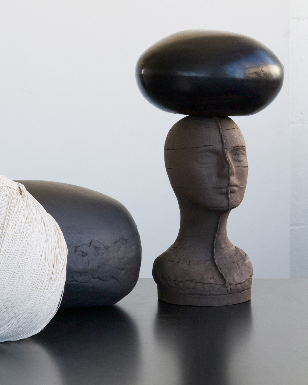 In contrast to the unglazed naked head, the carried and un-carried orb-vessels are hand-polished and waxed terra sigilatta, fiber or hand-blown glass.